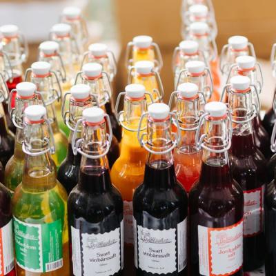 Lokalproducerad dryck i olika färger i glasflaska på ett bord