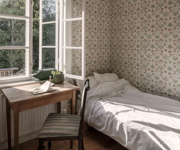 Säng och skrivbord på pensionat