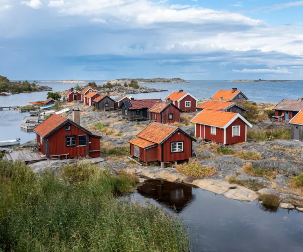 EN karg ö i ytterskärgården. Röda små stugor med tegeltak och vita eller svarta knutar.