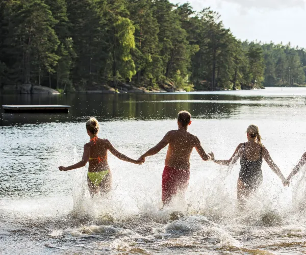 Badande ungdomar i en sjö med träd runt