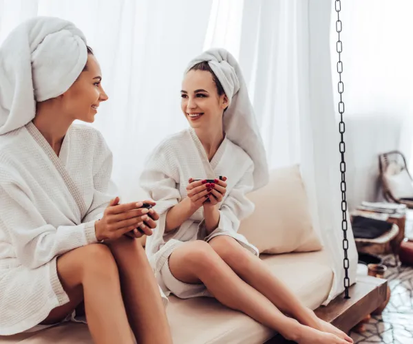 Två kvinnor i vita badrockar på ett spa