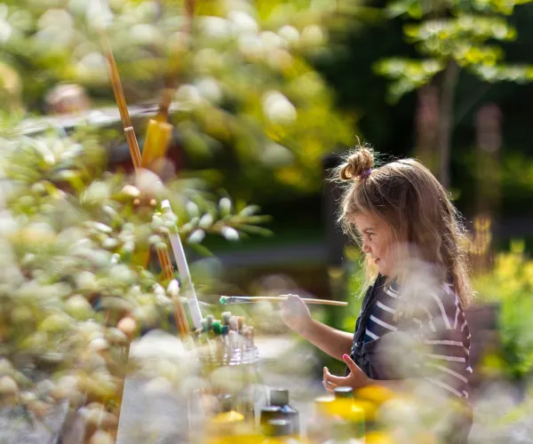 Flicka som målar en tavla i grönskan