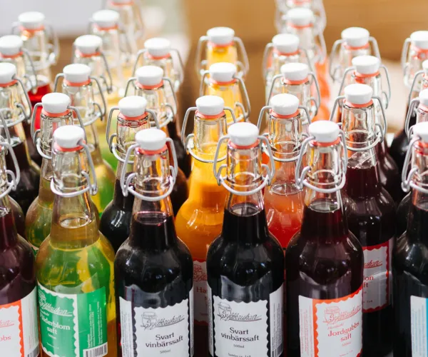 Lokalproducerad dryck i olika färger i glasflaska på ett bord