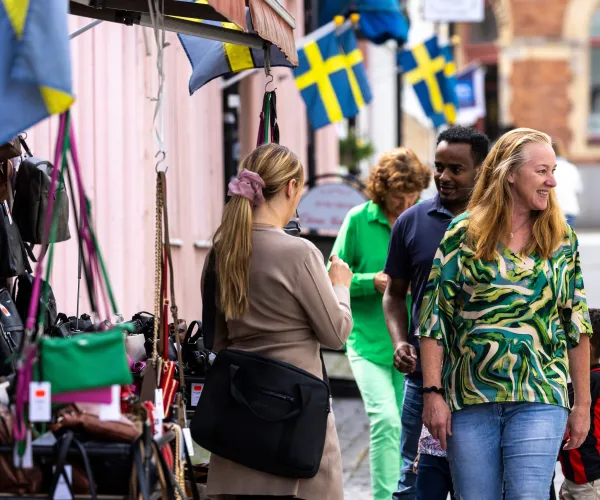 Folk på en gågata, utanför en väskaffär