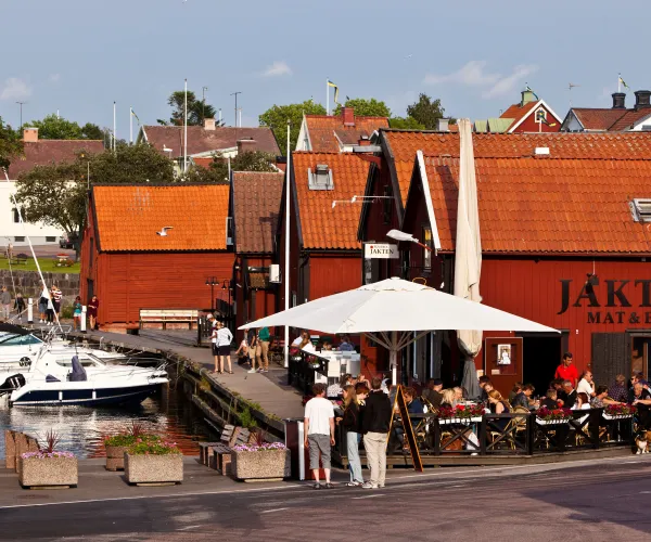 Skärgårdskrog i röda båthus med uteservering och båthamn